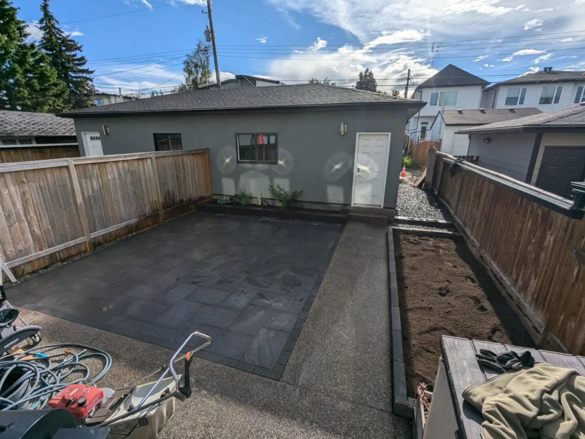 Charcoal slab patio between cedar fences in front of a detached garage